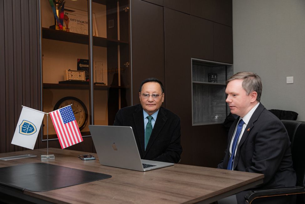 University representatives meet at a desk displaying AUM and American flags.